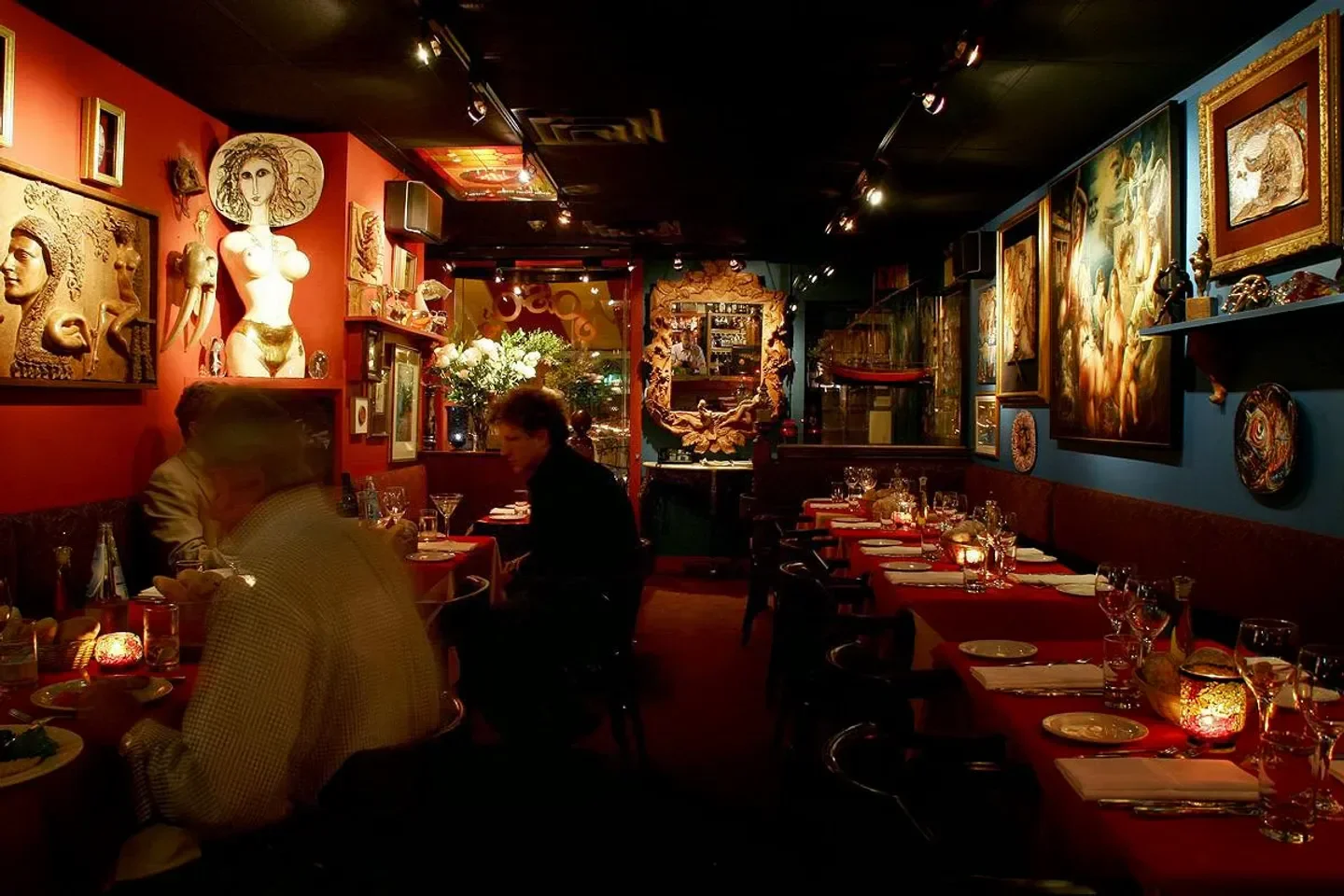 Cozy interior of Joso's restaurant in Toronto, with red tables and artistic decor.