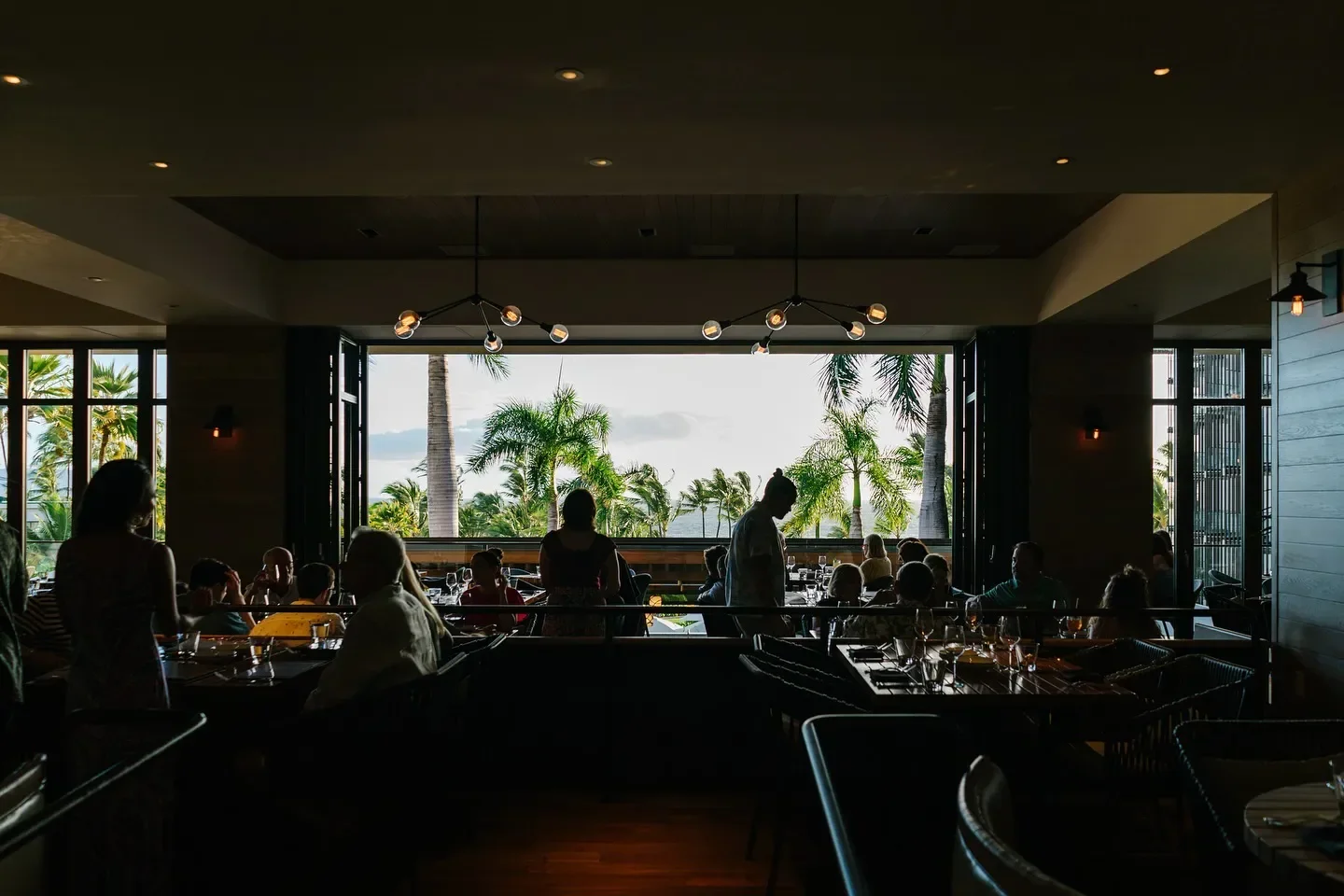 Dining at Ka'ana Kitchen in Maui, with views of palm trees and the ocean.