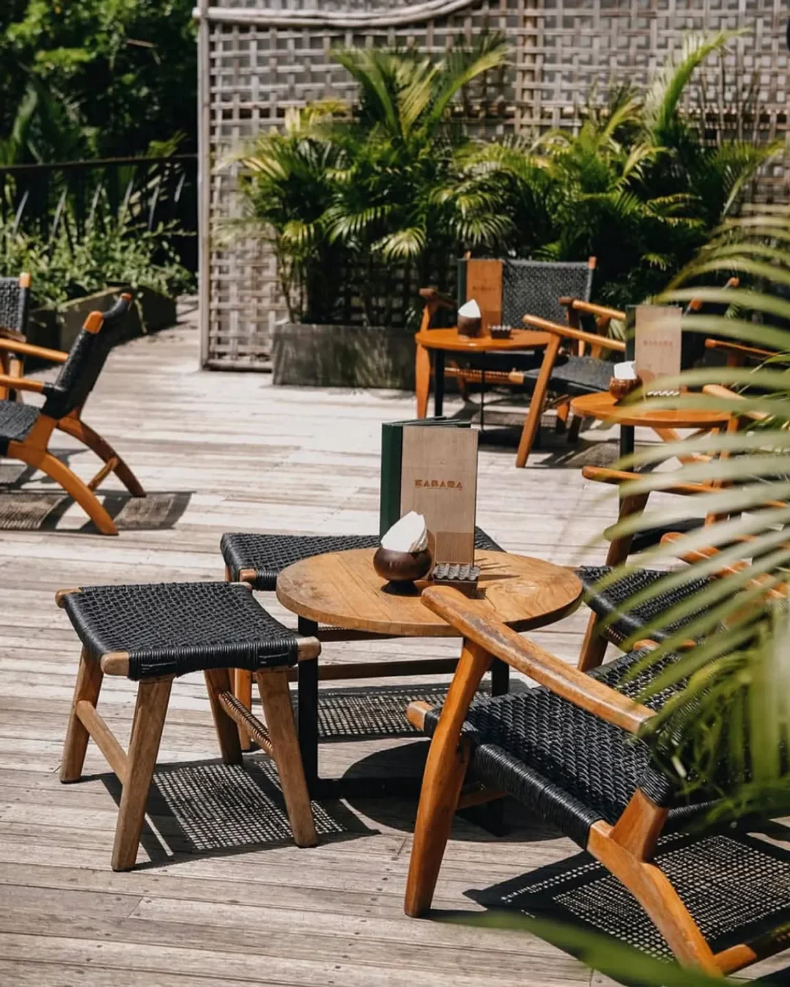 Outdoor seating at Kabana Ubud restaurant in Bali, with stylish wooden furniture and greenery.