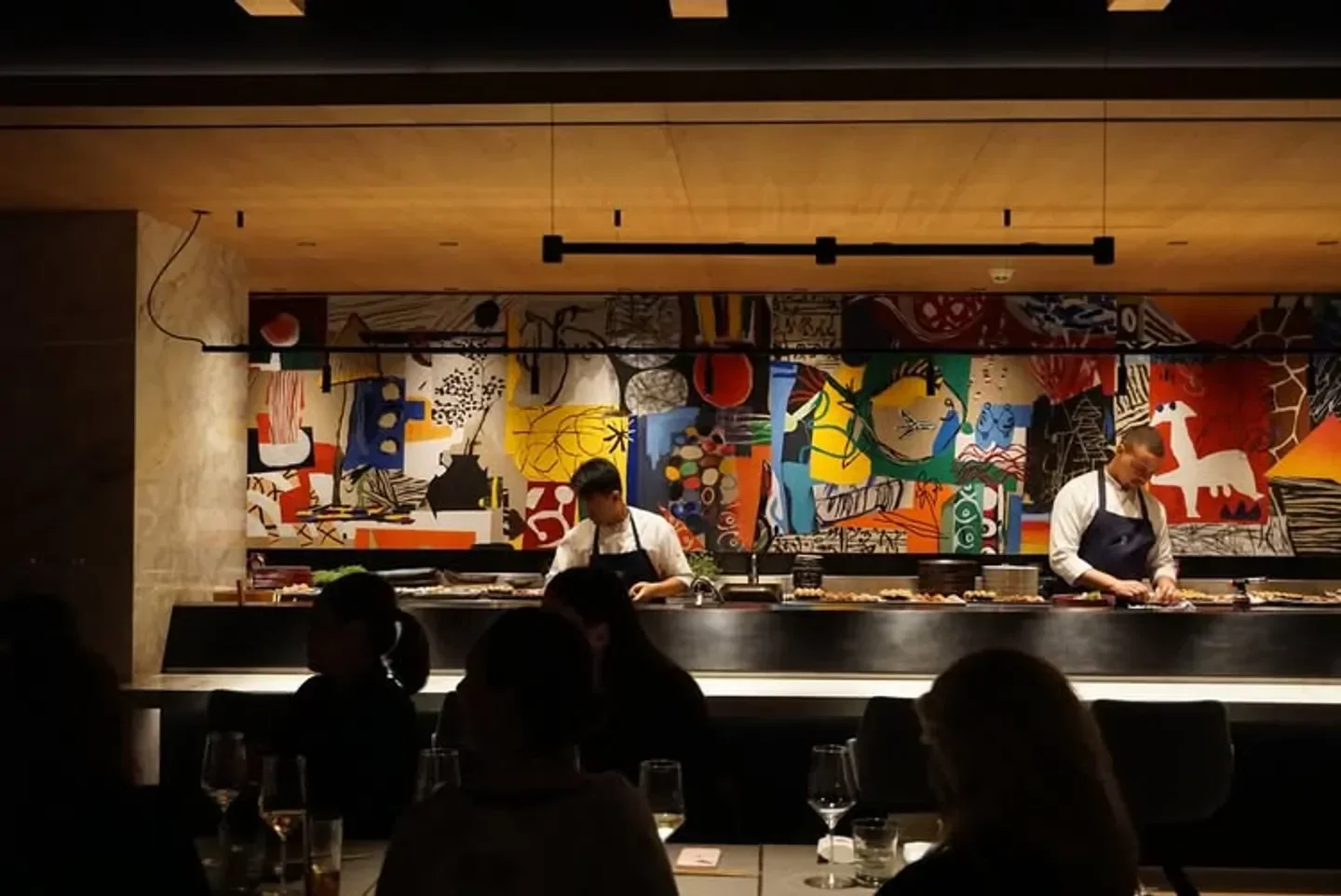 Chefs preparing food at Kabuki Lisboa restaurant in Lisbon, with unique art backdrop.