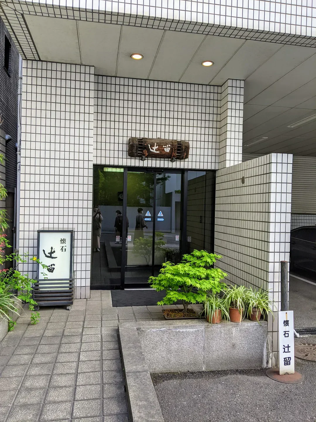 Entrance to Kaiseki Tsujitome restaurant in Tokyo, featuring traditional signage and landscaping.