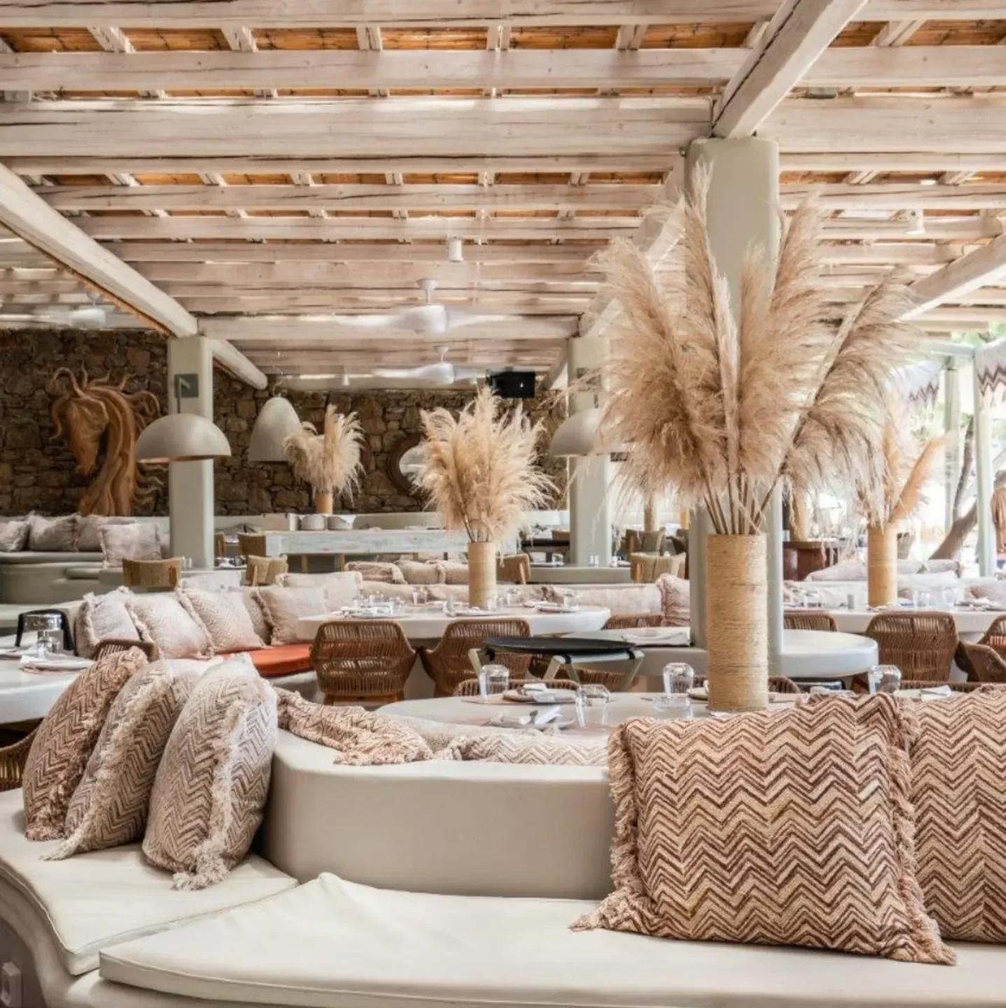 Cozy seating at Kalua Beach Bar in Mykonos, featuring decorative pillows and dried flowers.