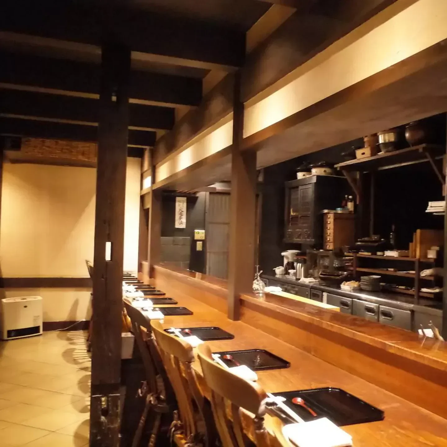 Interior of Kamigamo Akiyama restaurant in Kyoto, with wooden counter and seats.