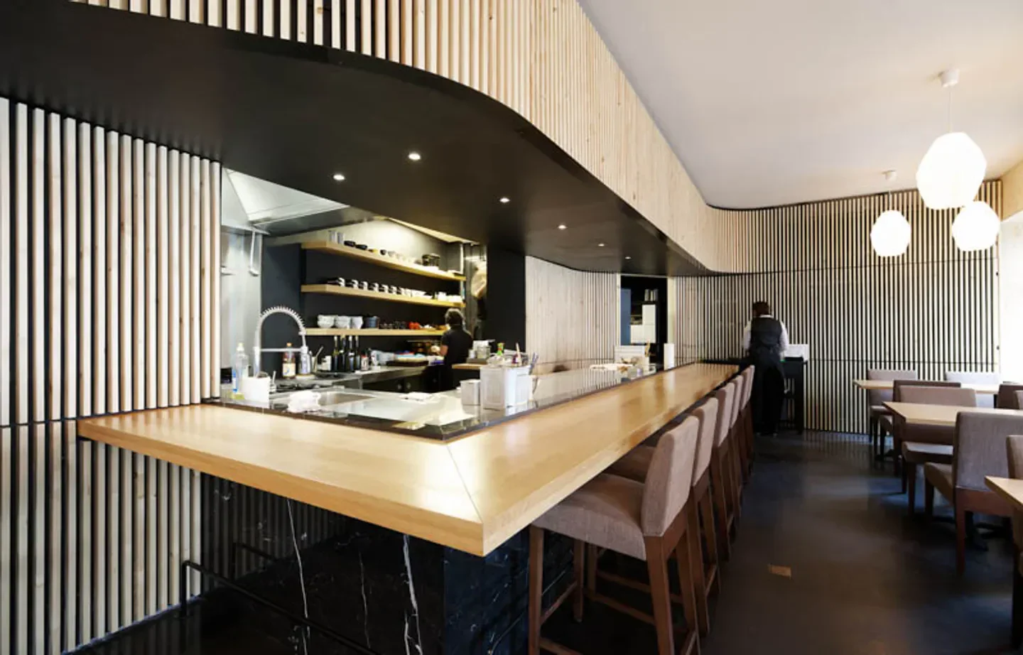 Interior view of Kamo restaurant in Brussels, featuring a stylish wooden bar.