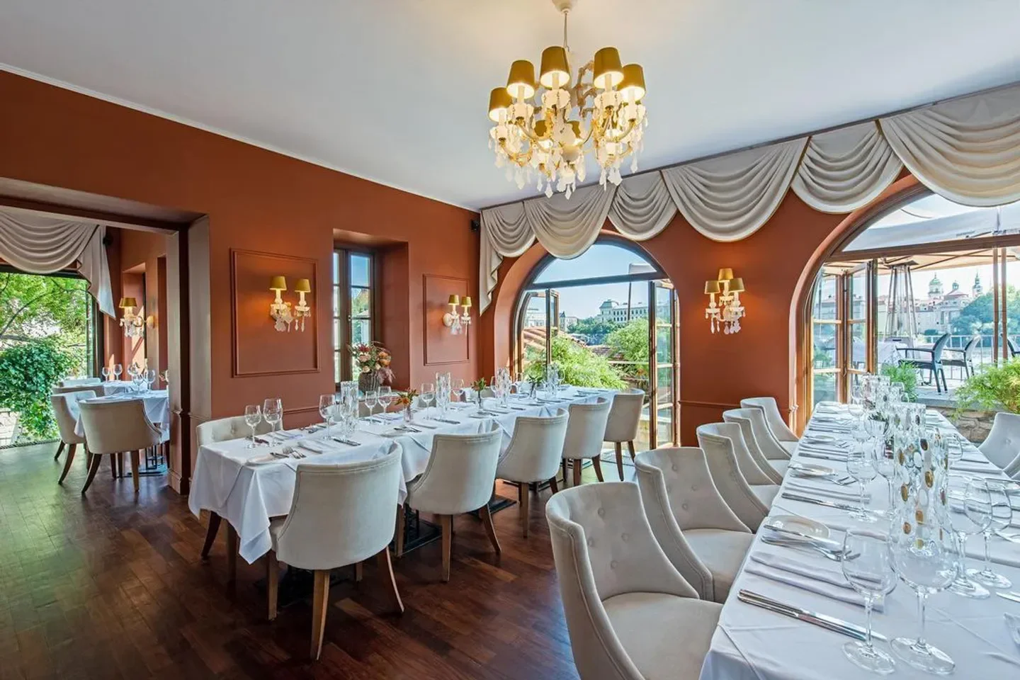 Elegant dining room at Kampa Park restaurant in Prague, with views and chandeliers
