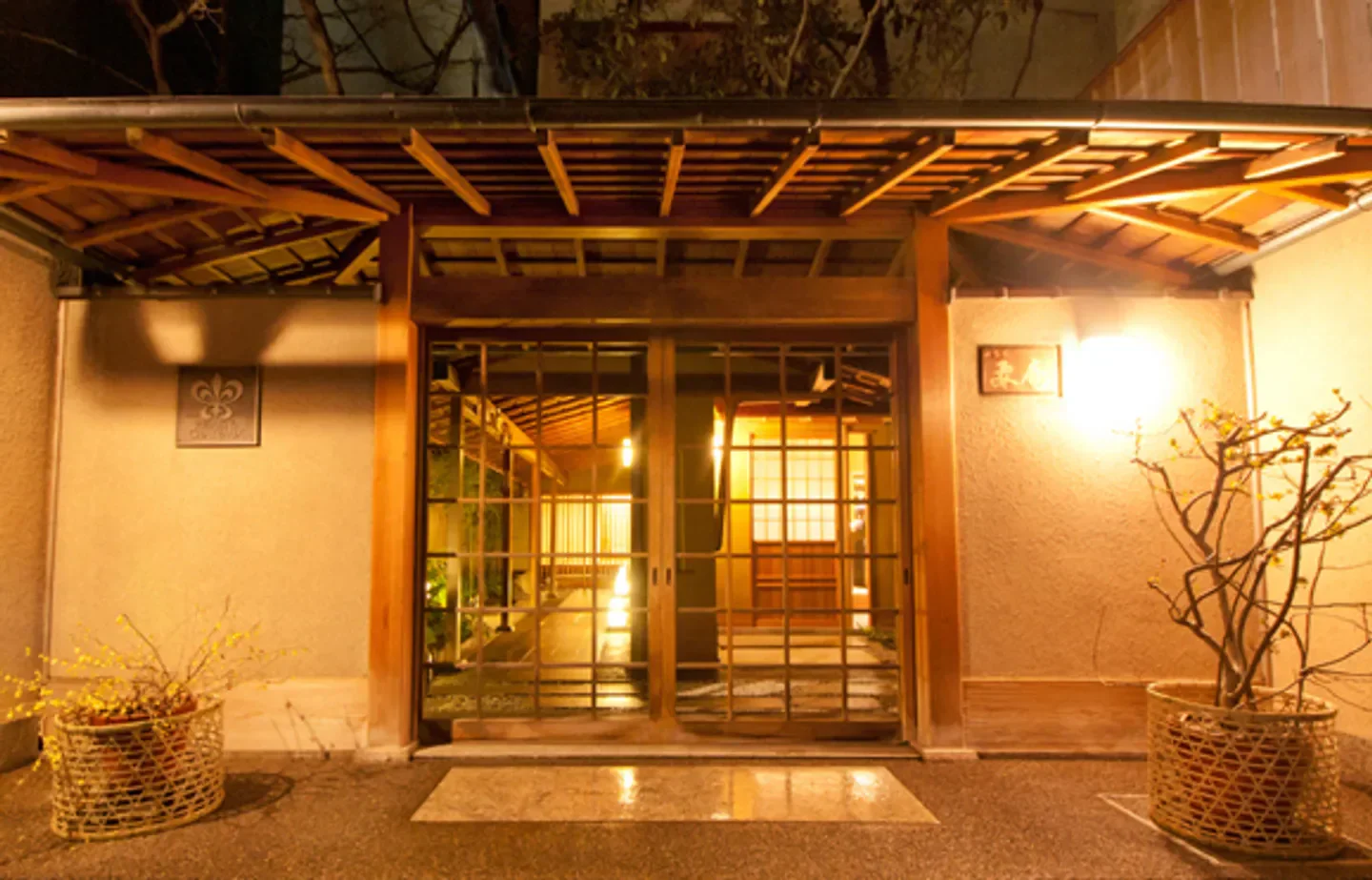 Entrance to Kanamean Nishitomiya restaurant in Kyoto at night, with warm lighting.