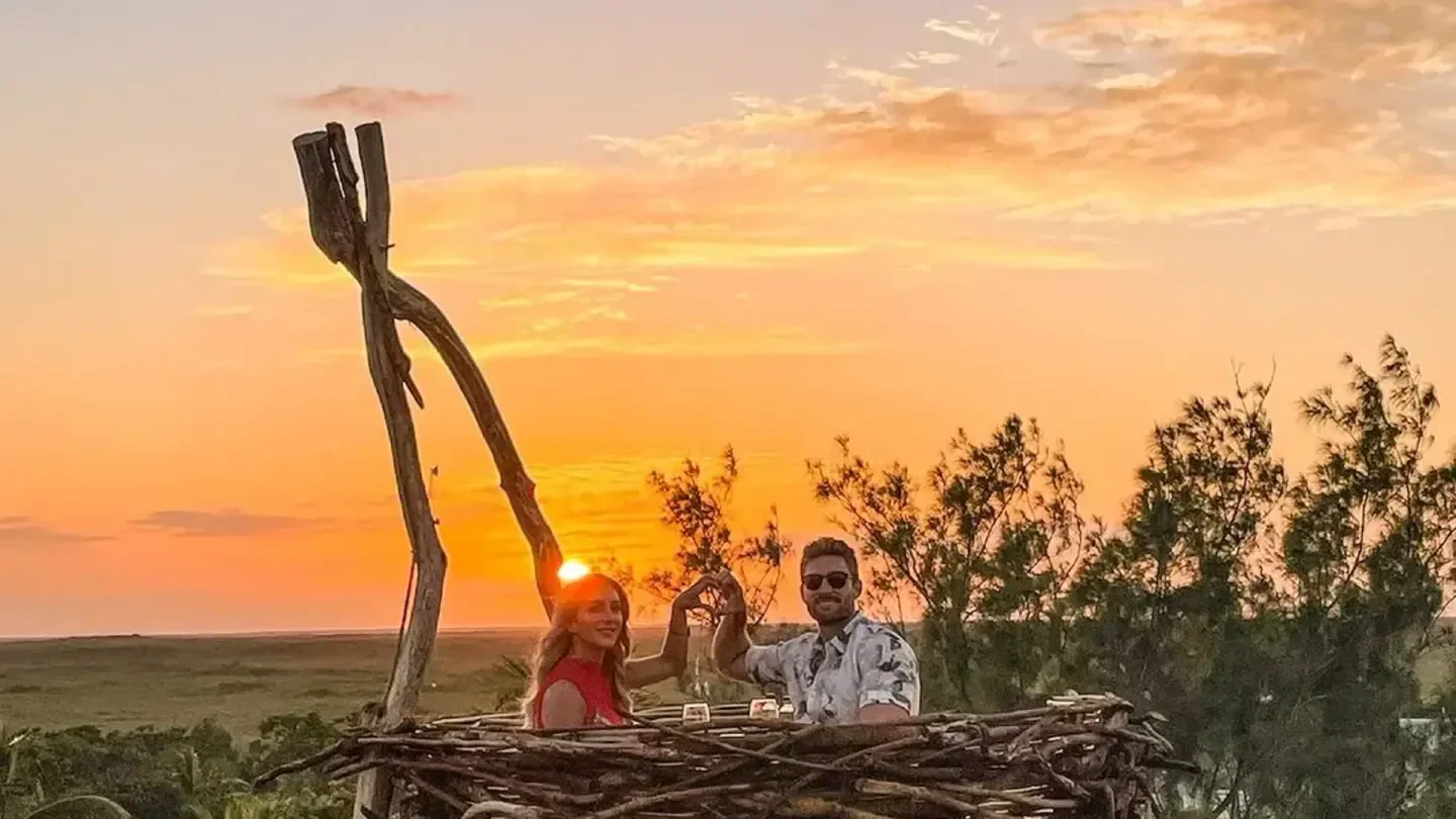 Couple enjoying sunset at Karma nightclub in Tulum, Mexico, with heart gesture.