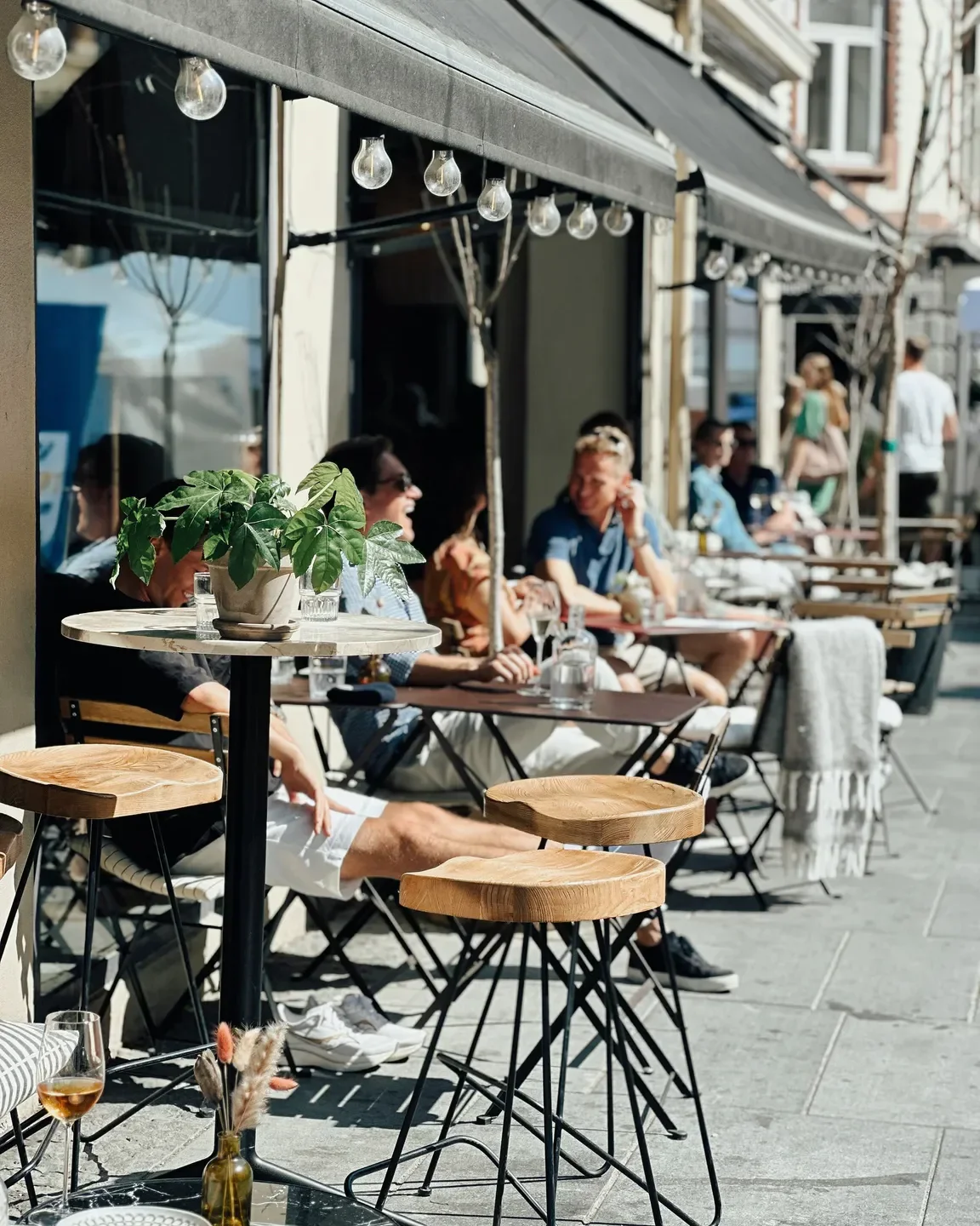 Outdoor seating at Kastellet restaurant in Oslo, featuring diners and sunny ambiance.