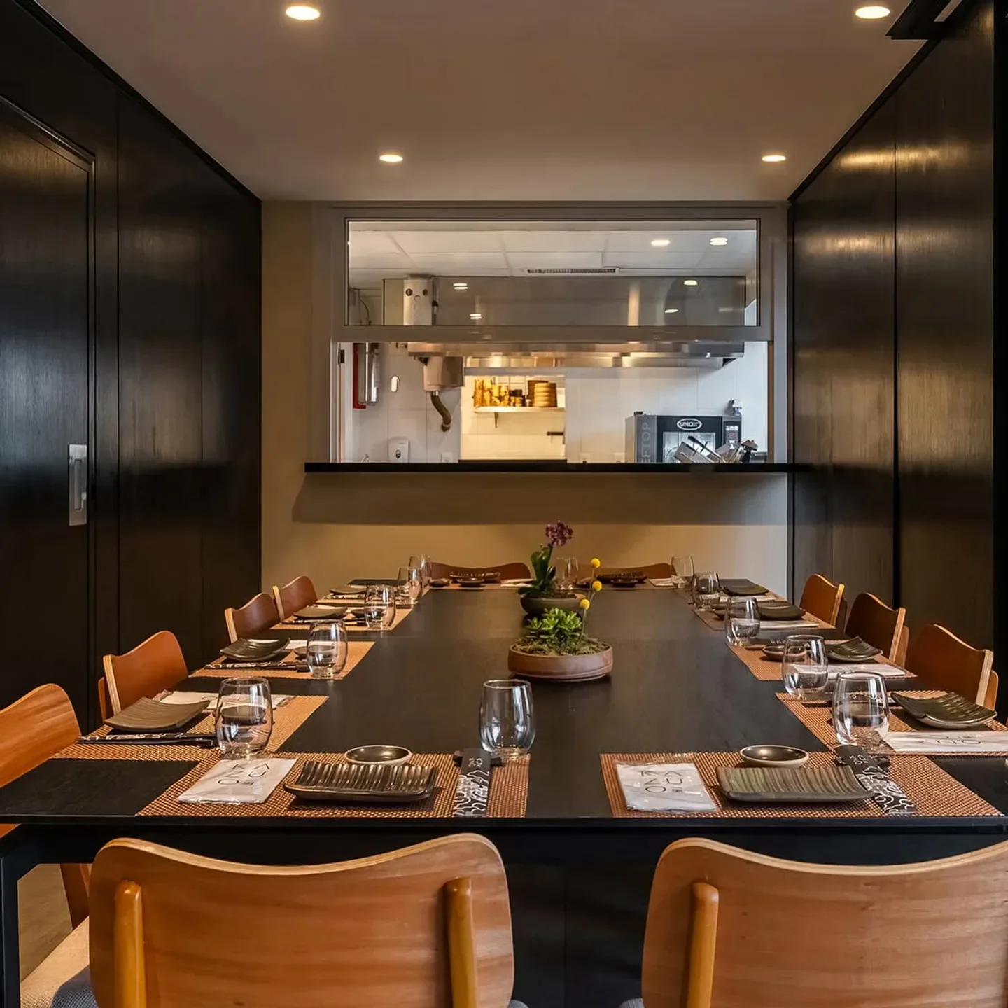 Elegant dining room interior at Kazuo restaurant in Sao Paulo with kitchen view.