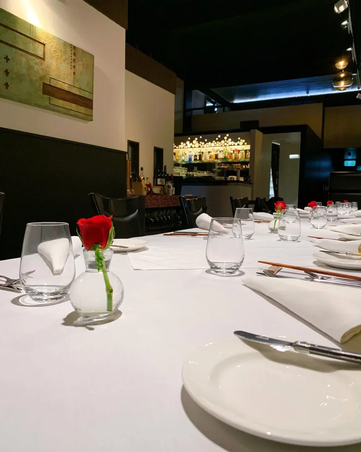 Elegant dining table setting at Kazuya restaurant in Auckland, with rose and glasses.