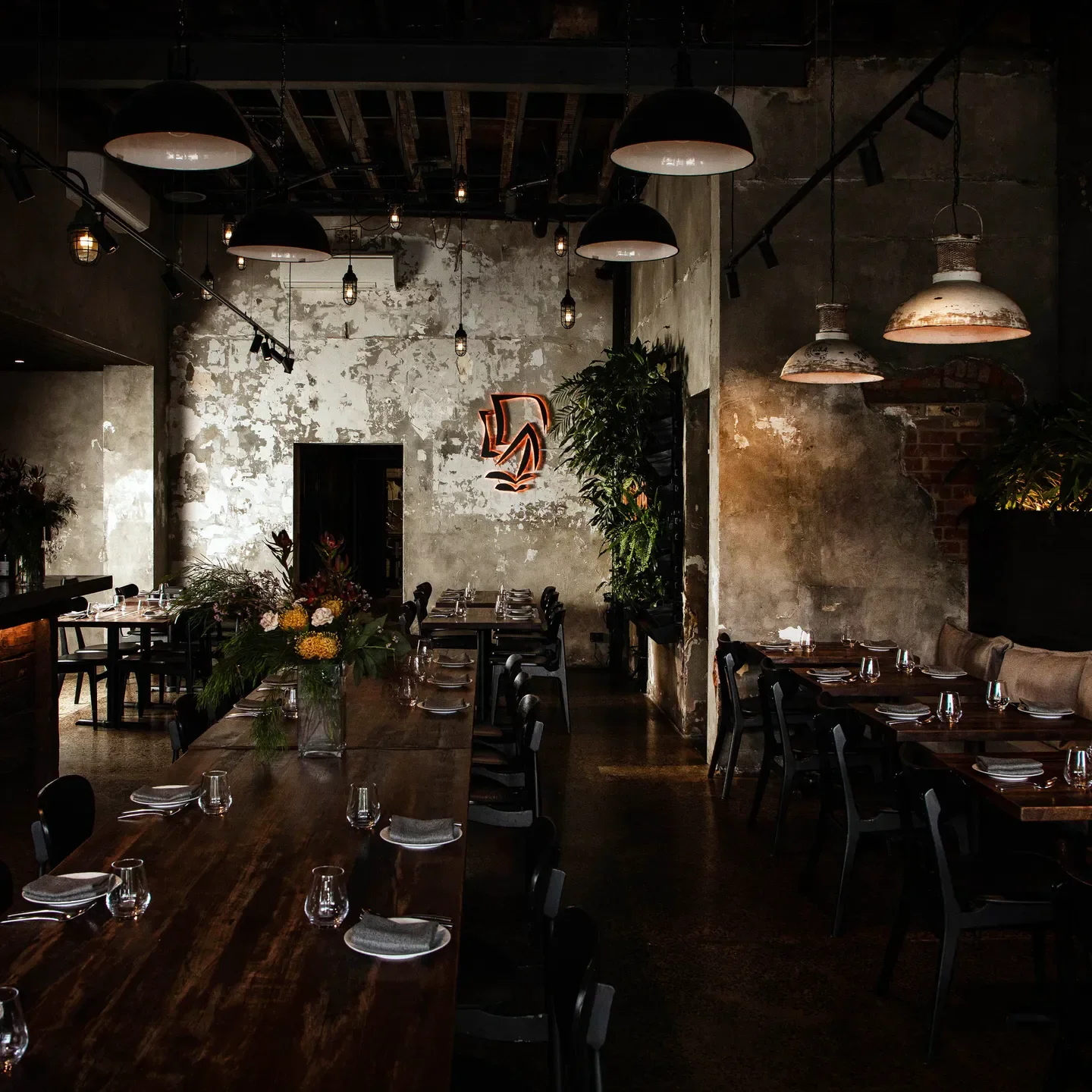 Interior of Kekou restaurant in Melbourne, featuring long wooden tables and moody lighting.