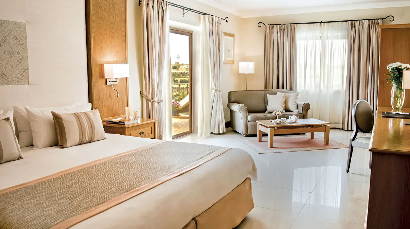 Spacious bedroom at Kempinski Hotel San Lawrenz, Malta, with balcony overlooking the landscape
