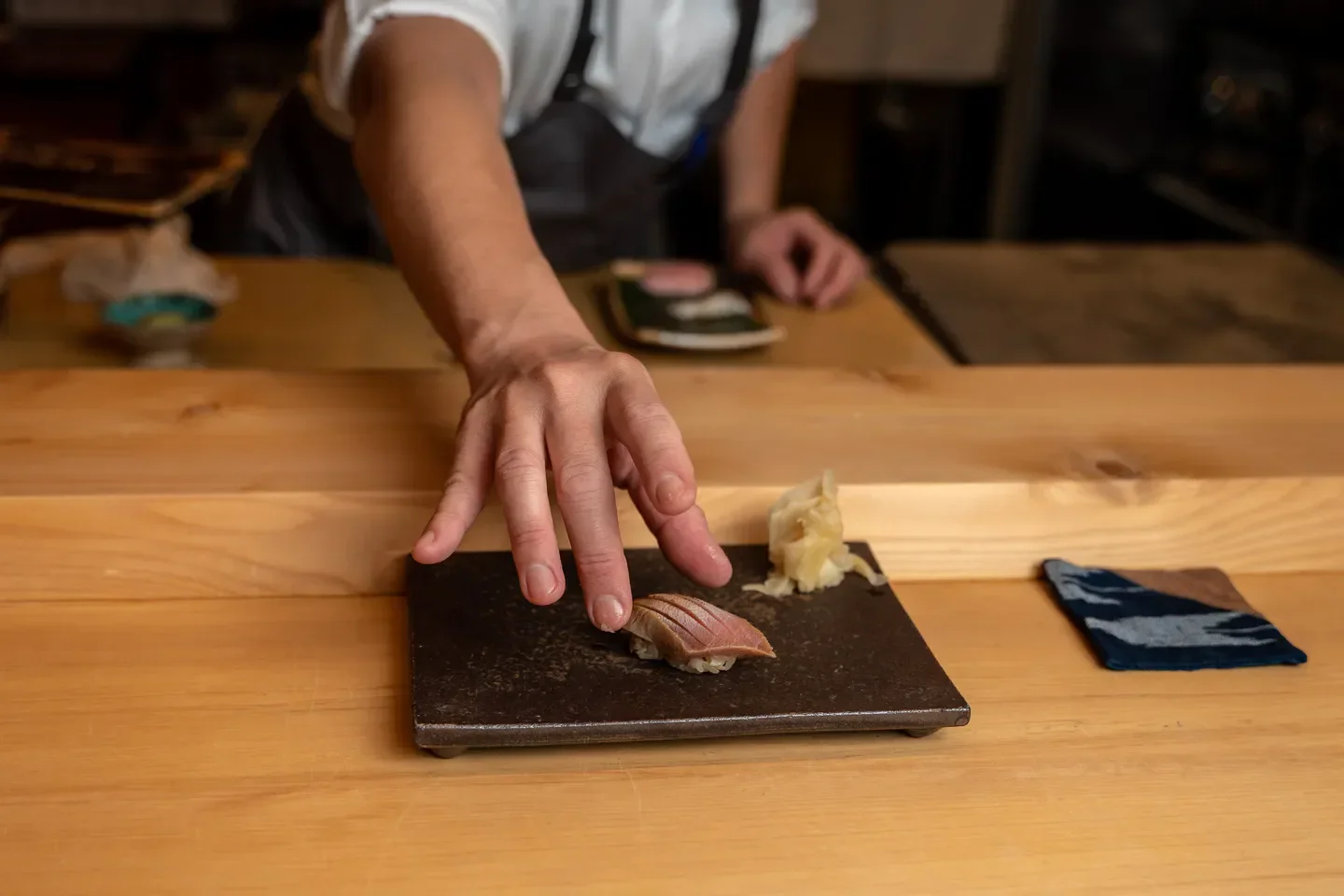 Chef placing sushi at KEN restaurant in San Francisco; preparing a delicious dish.