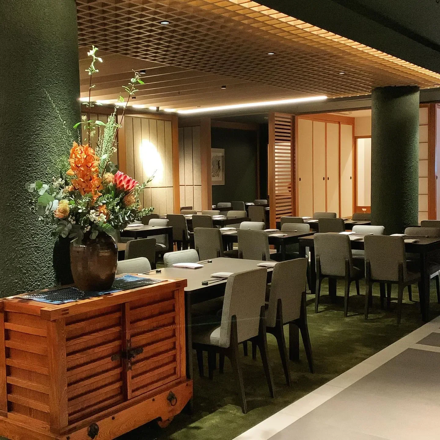 Interior dining space at Kenzan in Melbourne, featuring tables, chairs and flower arrangement.