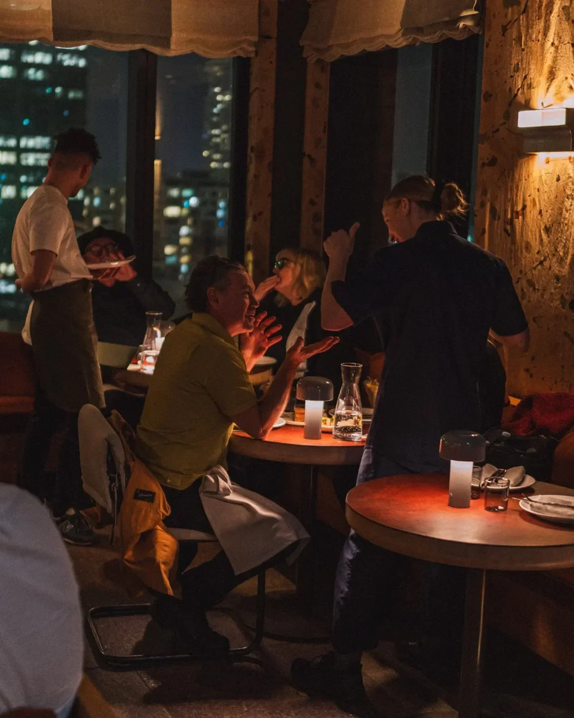 Dining scene at Kiln restaurant in Sydney, with city views at night.