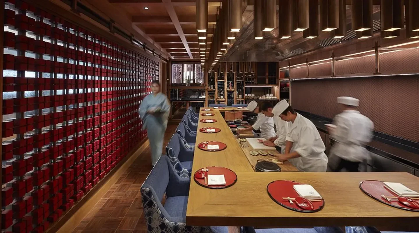 Interior view of Kinu by Takagi in Bangkok, with chefs preparing food at the counter.