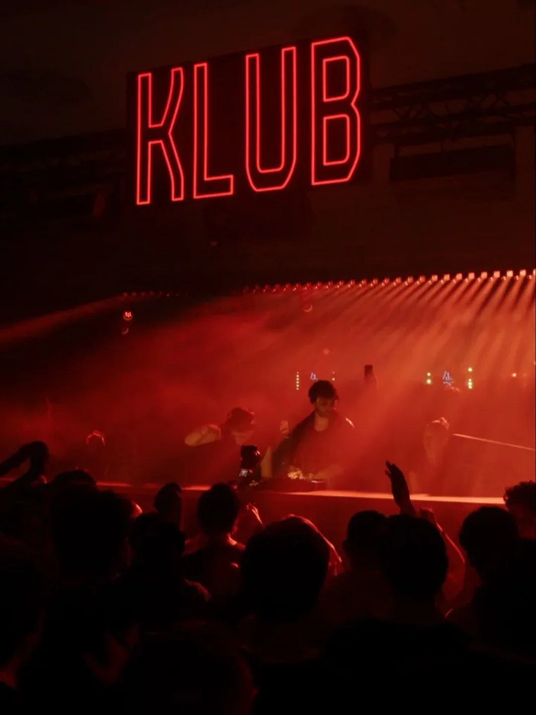 Red neon KLUB sign illuminates energetic crowd at a lively nightclub in Cannes