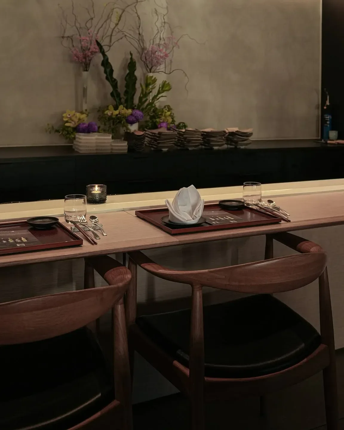Elegant dining setup at KOMEYUI Melbourne restaurant, featuring wooden chairs and floral arrangements.