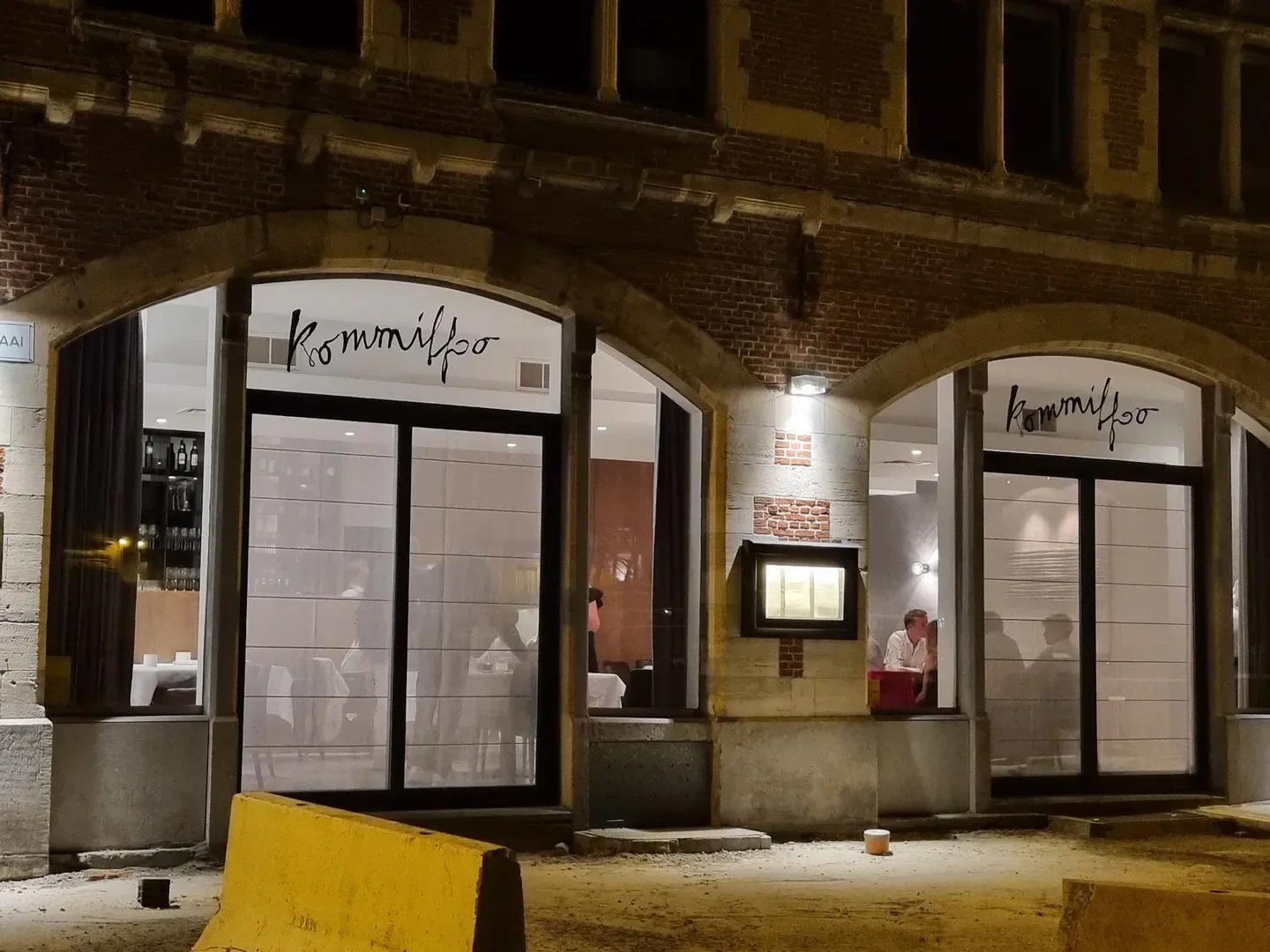 Exterior of Kommilfoo restaurant in Antwerp, Belgium, featuring illuminated windows and inviting ambiance.