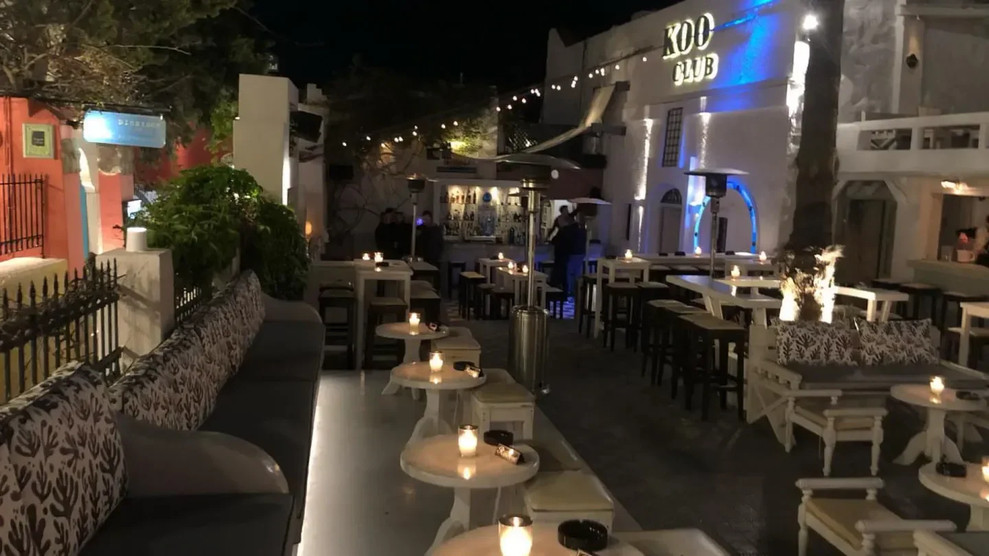 Night view of Koo Club in Santorini, showcasing tables, seating, and outdoor bar