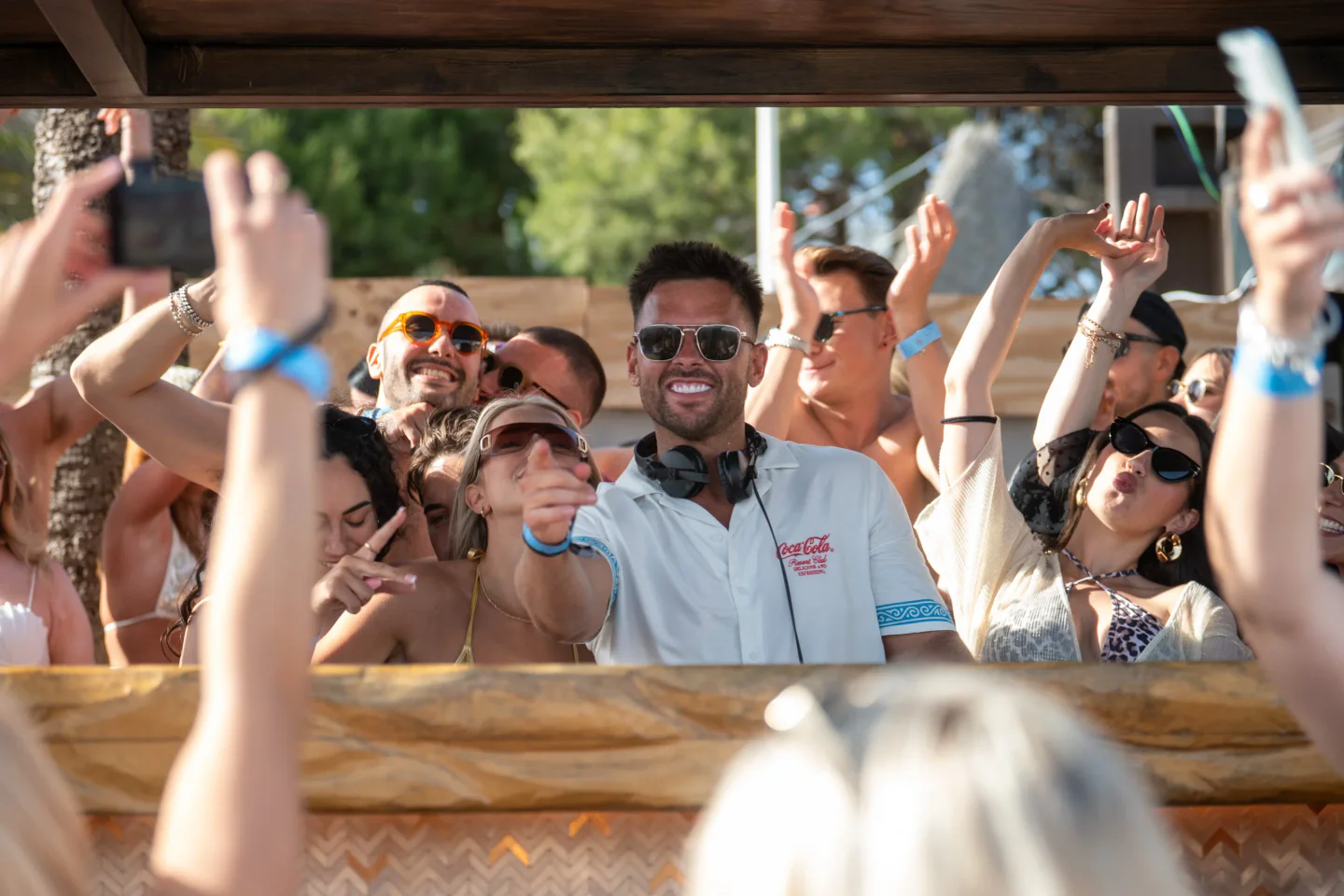 DJ at Kova Beach Club in the city, entertaining a crowd with hands in the air.