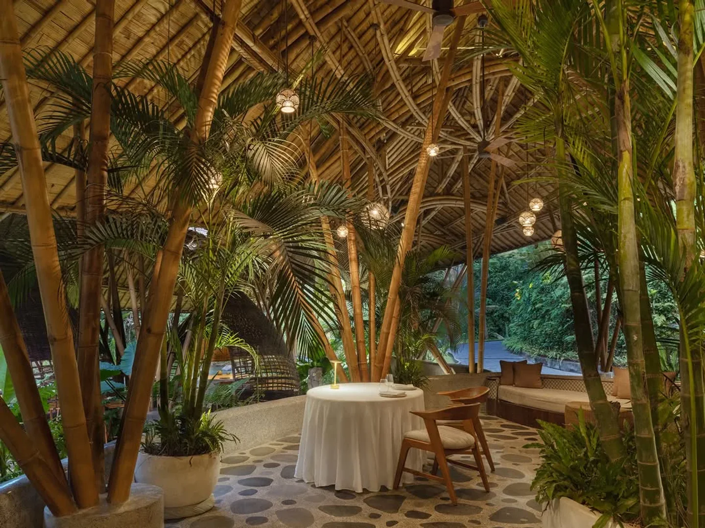 Tropical lush greenery surrounds a table at Kubu at Mandapa restaurant in the city.