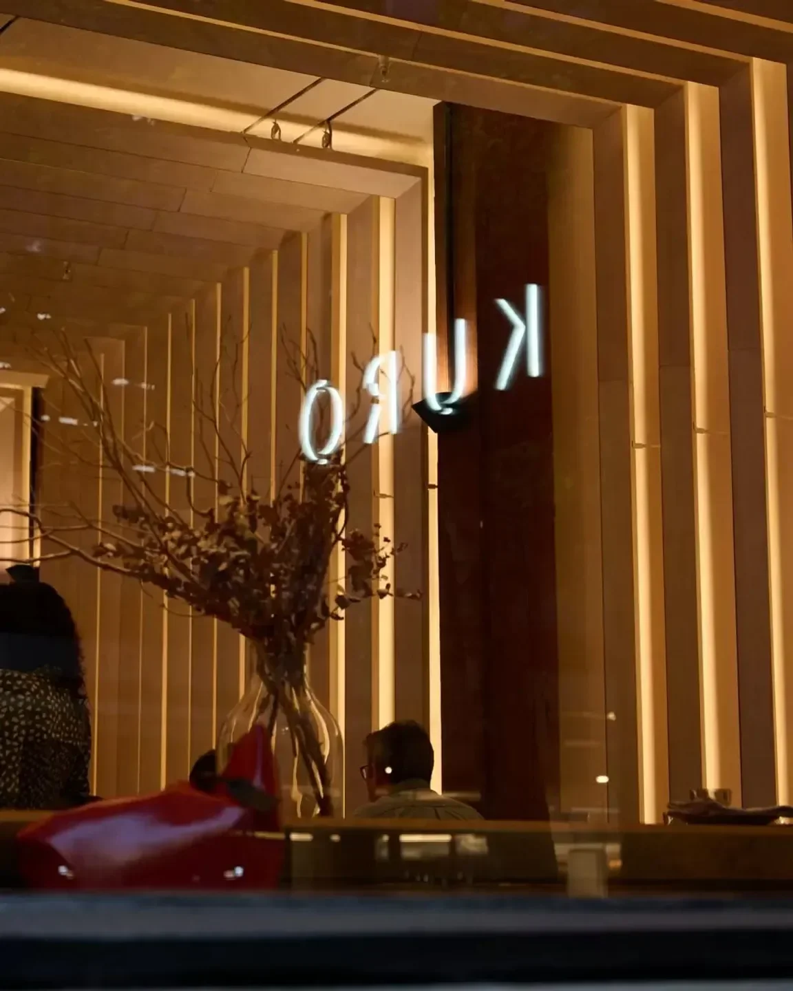 Exterior view of Kuro Bar & Dining in Sydney, featuring neon sign and warm lighting.