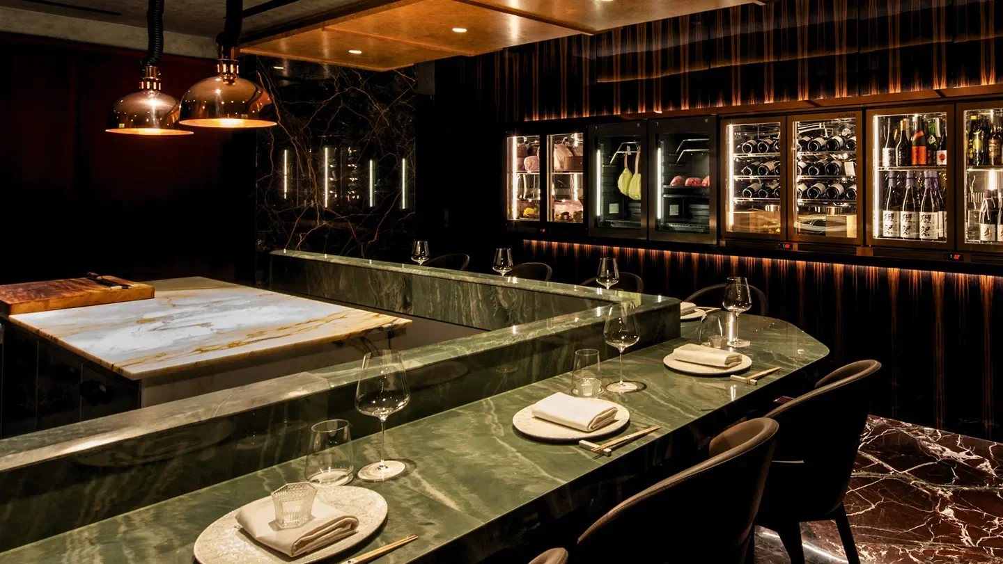 Interior of Kūza restaurant in Singapore, featuring marble bar and modern design.