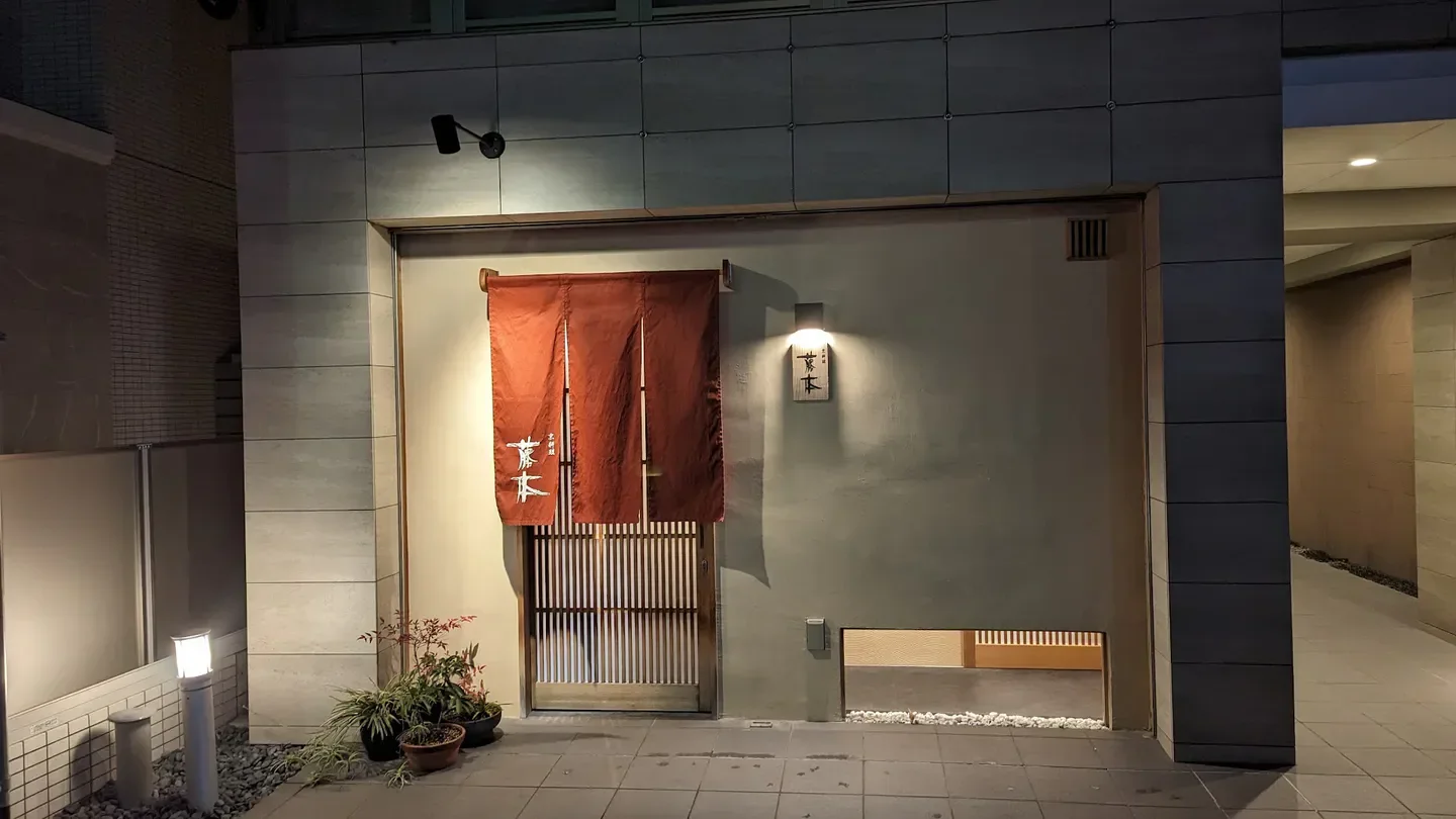 Exterior of Kyoryori Fujimoto in Kyoto, Japan, entrance at night with red curtain.