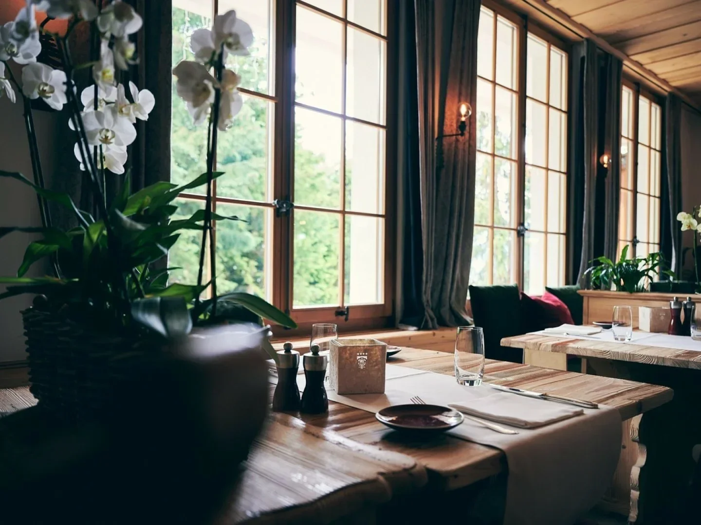 Cozy dining room at La Bagatelle restaurant in Gstaad, with flowers and natural light.