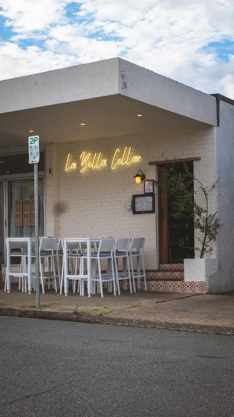 Exterior of La Bella Cellar restaurant in Gold Coast with outdoor seating and neon sign