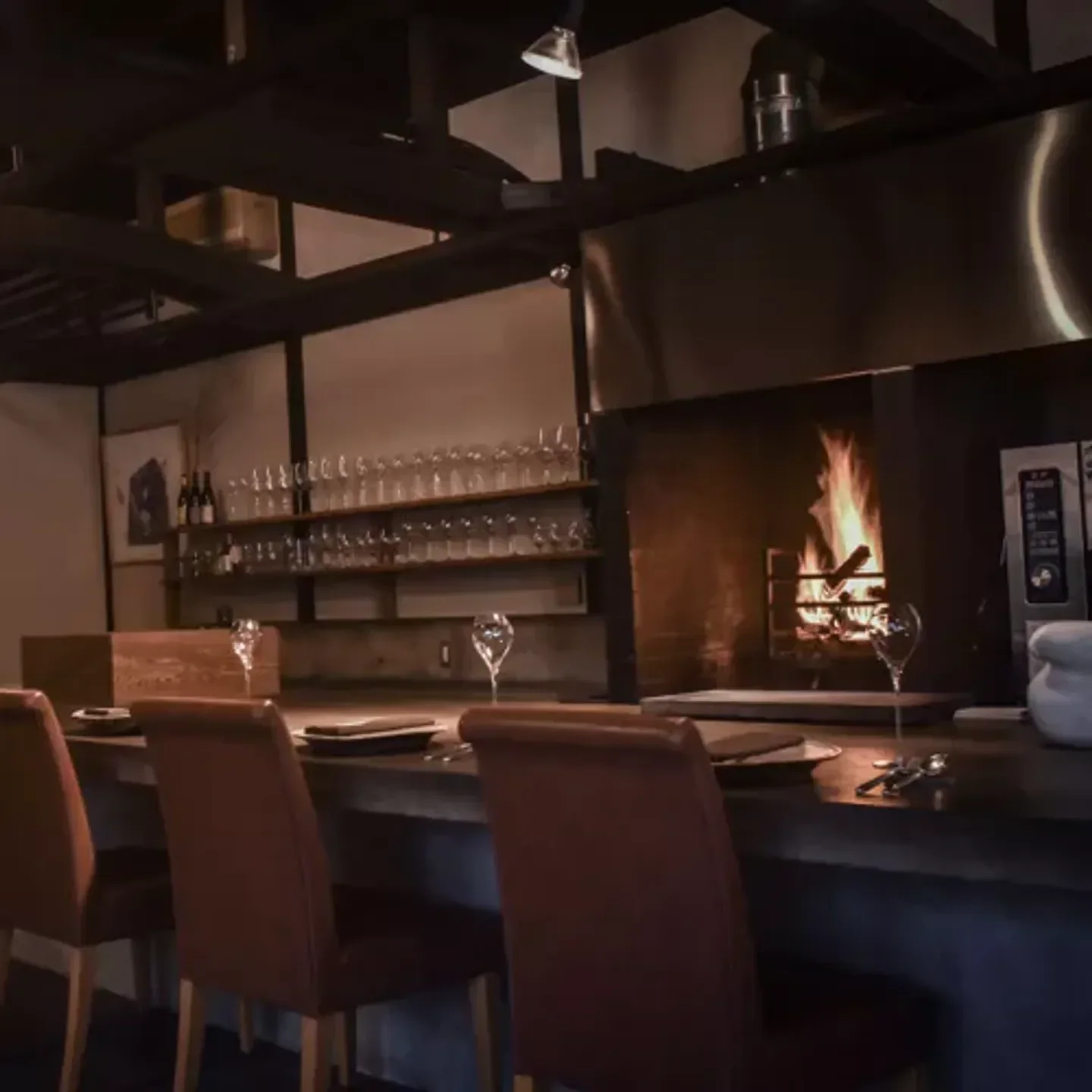 Cozy interior of la bûche in Kyoto with a fireplace and bar seating.