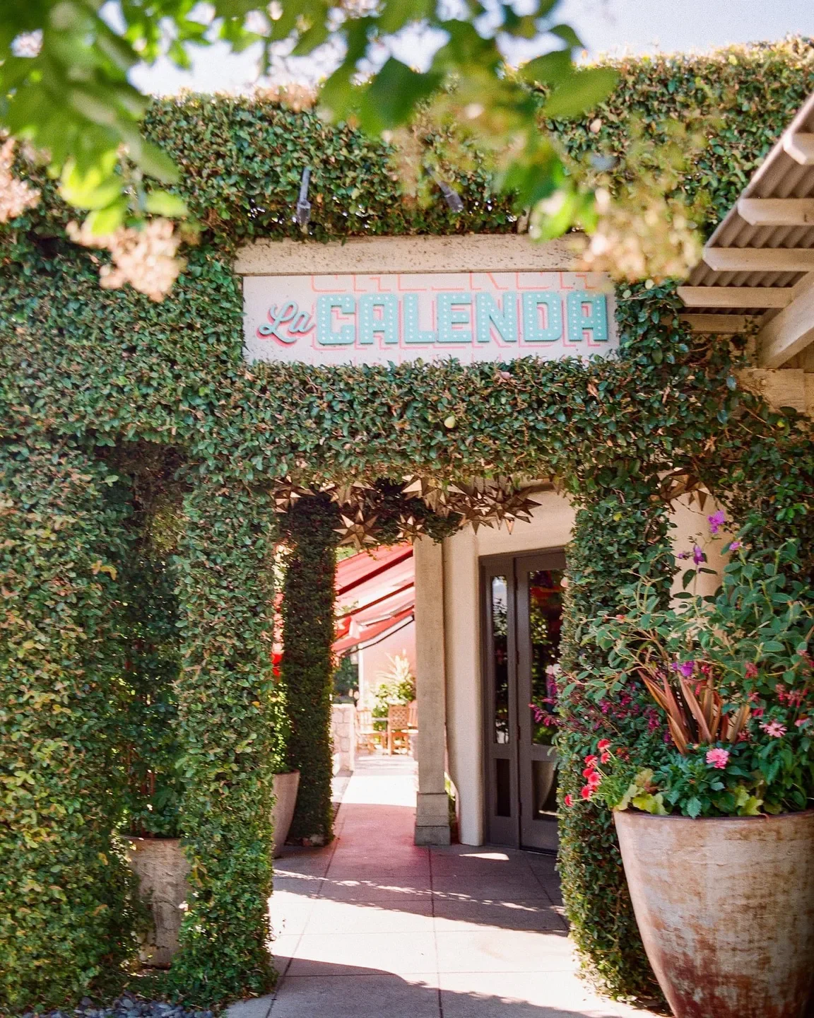 Entrance to La Calenda restaurant in Napa Valley, adorned with lush greenery and flowers.