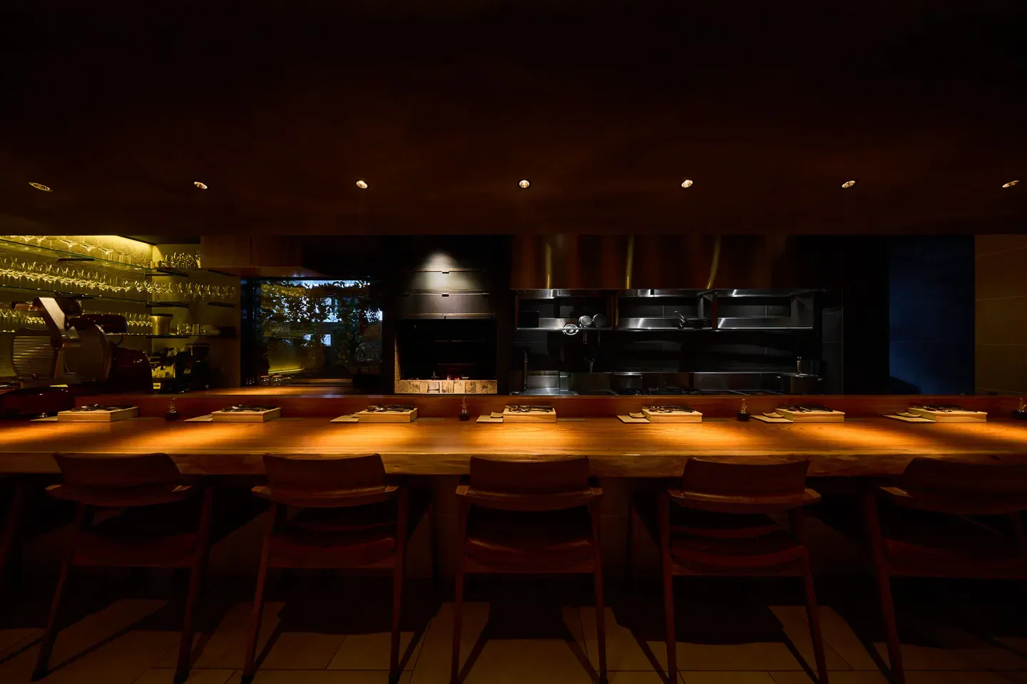 Interior of La Casa Tom Curiosa restaurant in Osaka, with wooden counter and chairs.