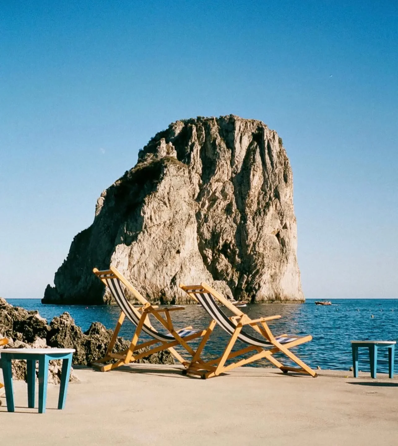 La Fontelina restaurant in Capri offers stunning views with deck chairs overlooking the Faraglioni rocks and sea.