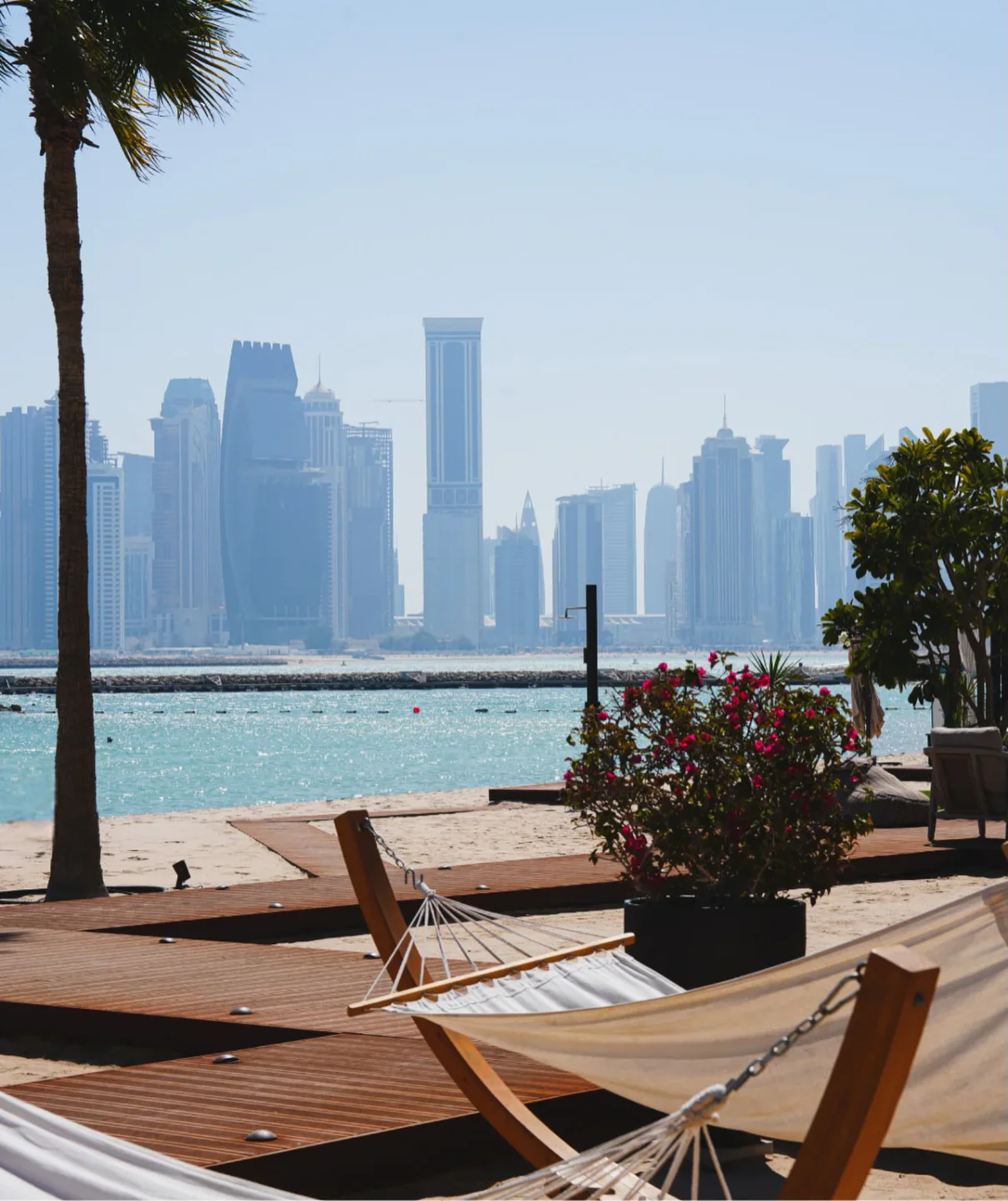 La Mar Beach overlooks the city skyline with hammocks on the sand and palm trees.