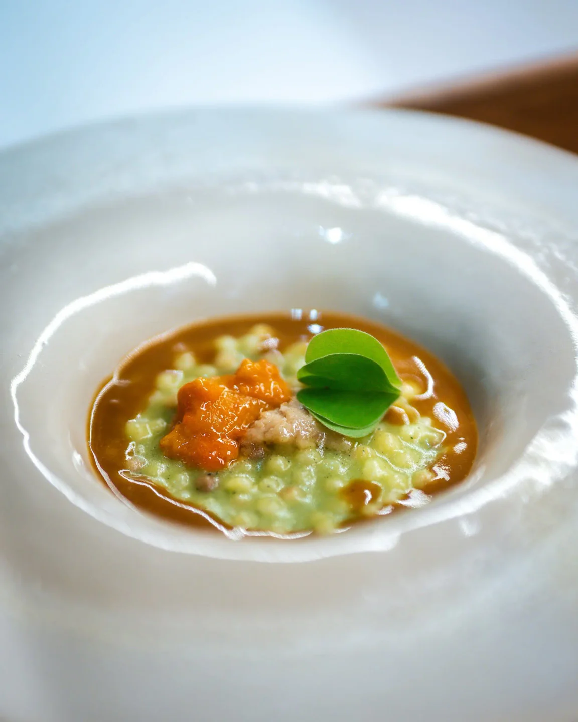 Gourmet seafood risotto with bright orange roe and microgreens at La Saletta Alghero restaurant in the city.