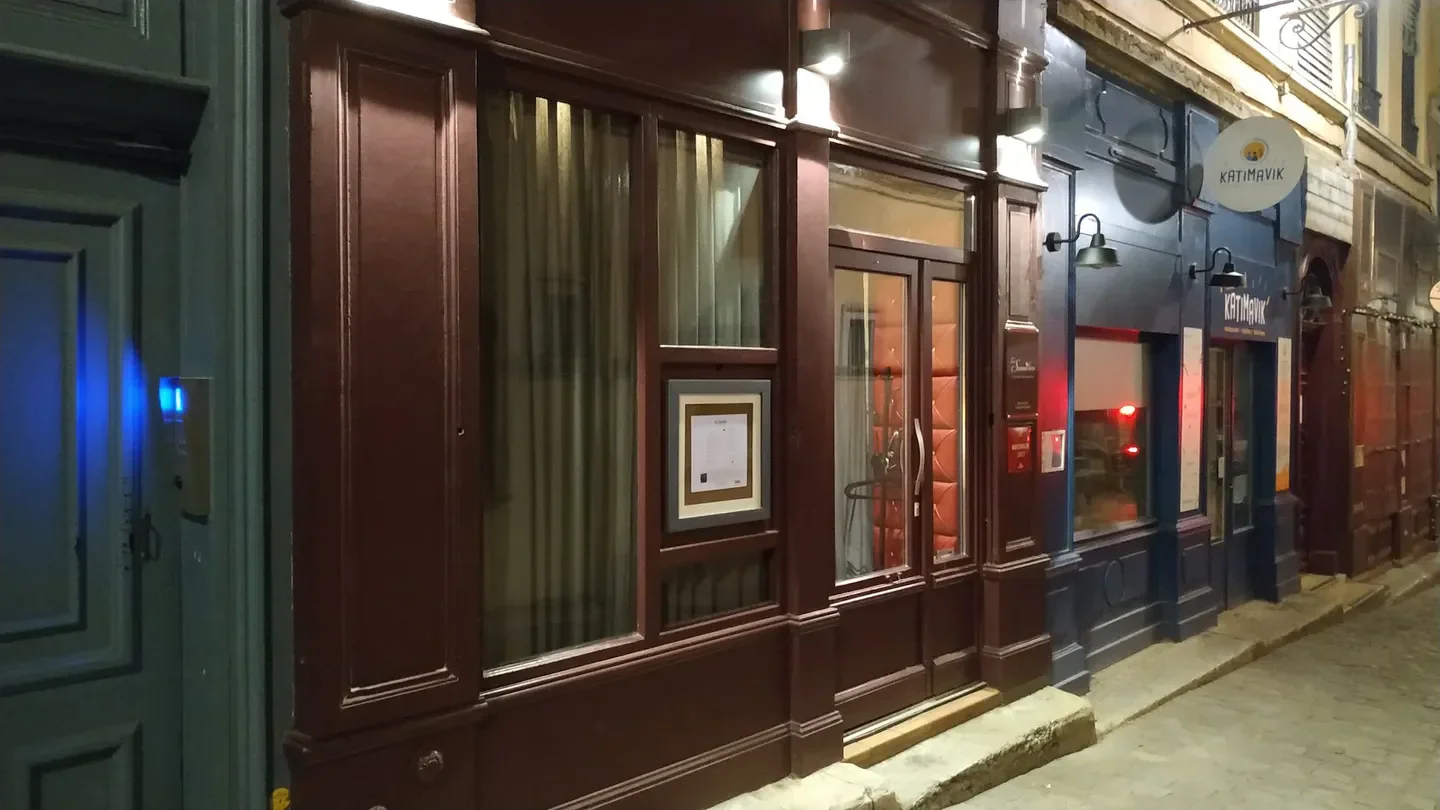 Entrance of La Sommelière restaurant in Lyon, France, at night with warm lighting.