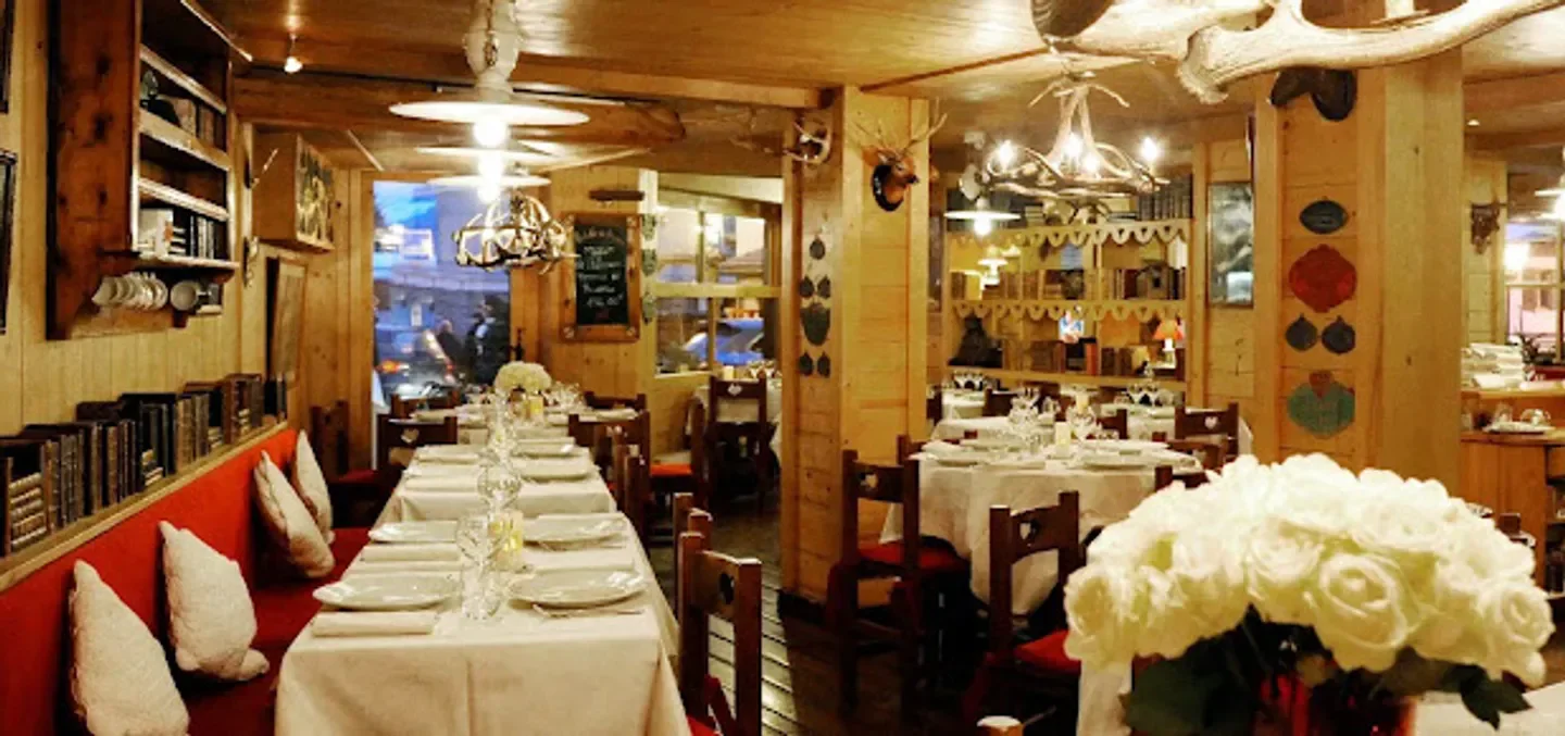 Cozy dining room at La Table du Trappeur in Megeve, with wooden decor and tables set.