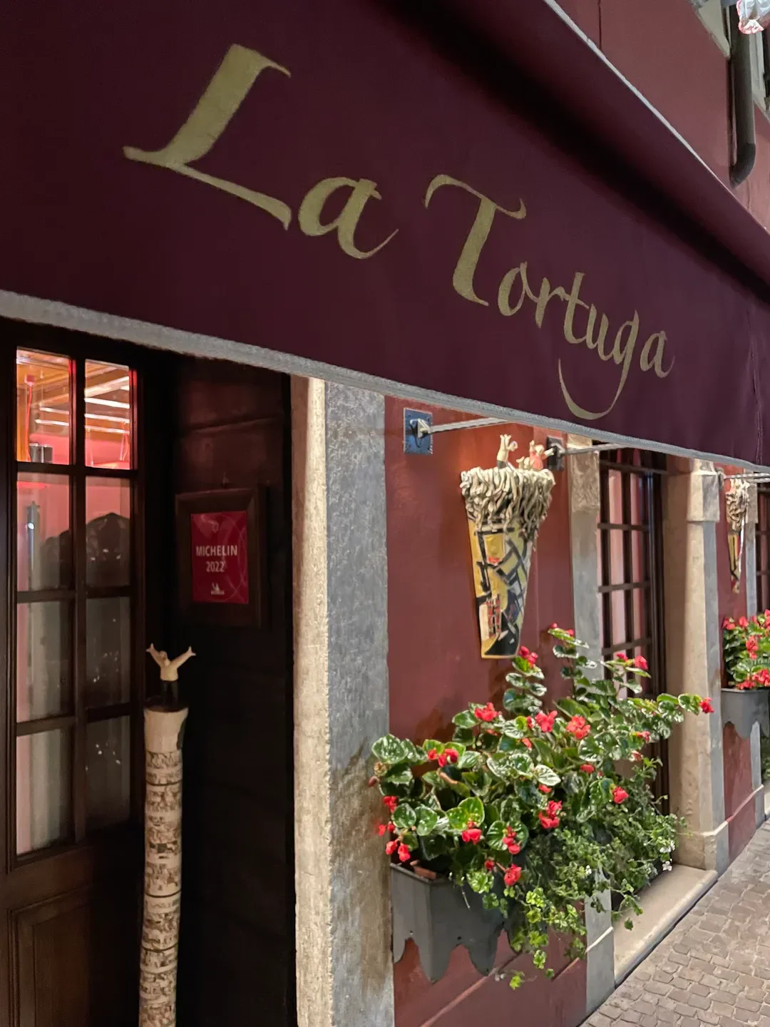 Exterior of La Tortuga restaurant in Lago di Garda with flowers and sign.