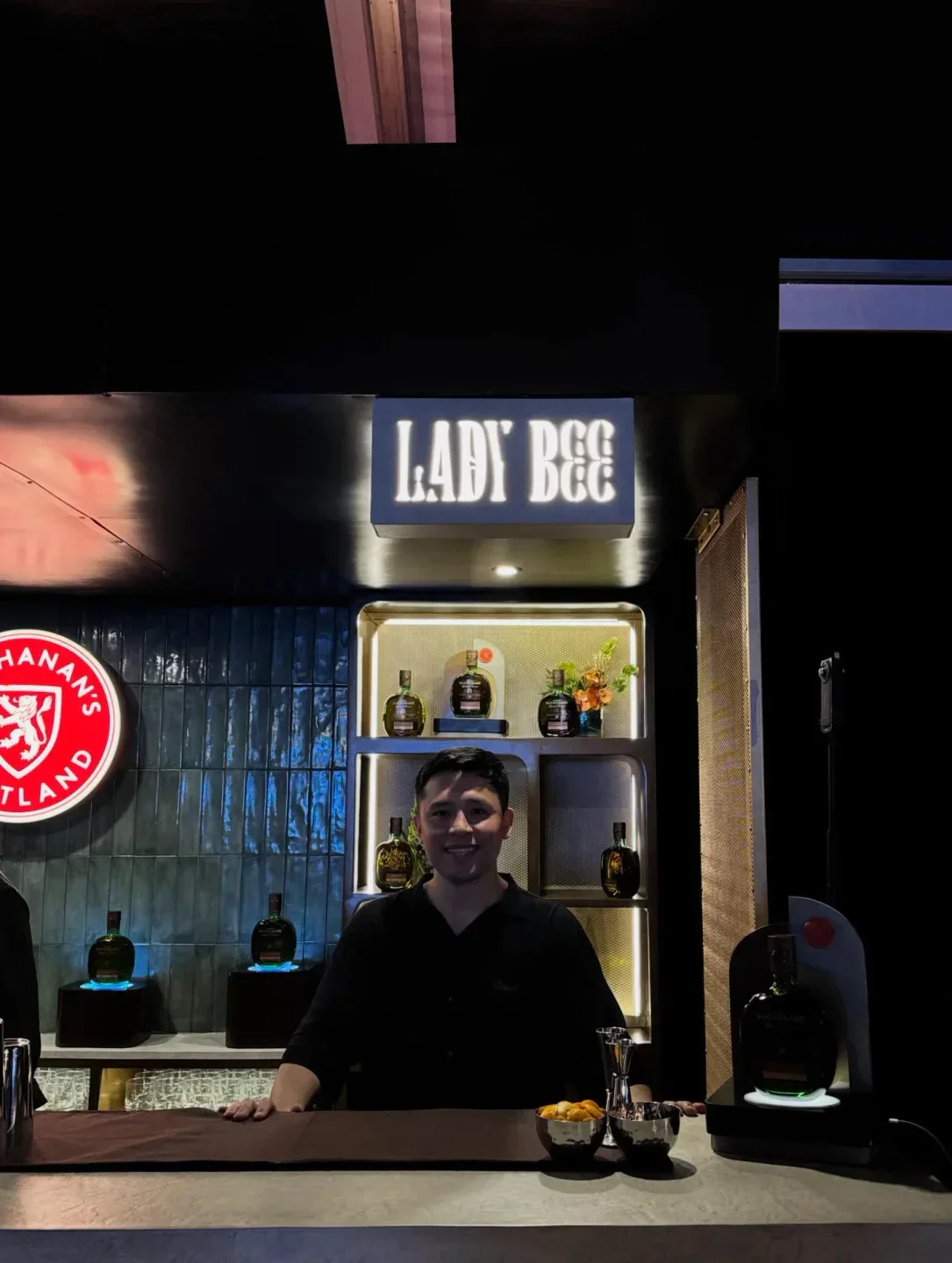 Smiling bartender at Lady Bee in Lima, Peru, with well-stocked bar and sleek decor.