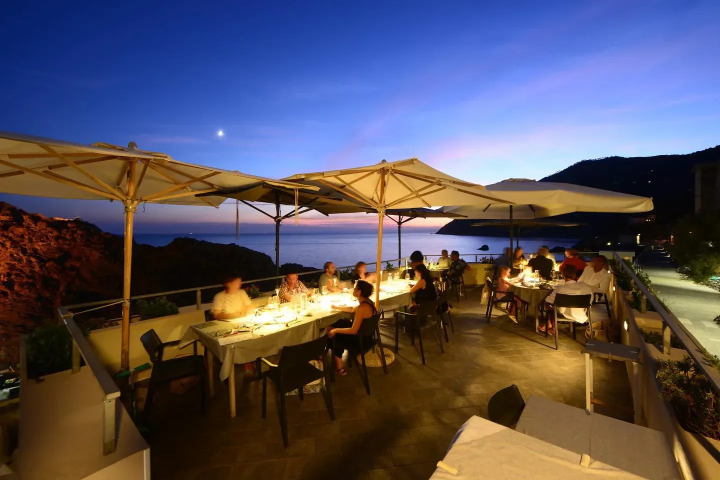 Outdoor dining at L’Agave Framura restaurant in Liguria, Italy, with beautiful sunset views.