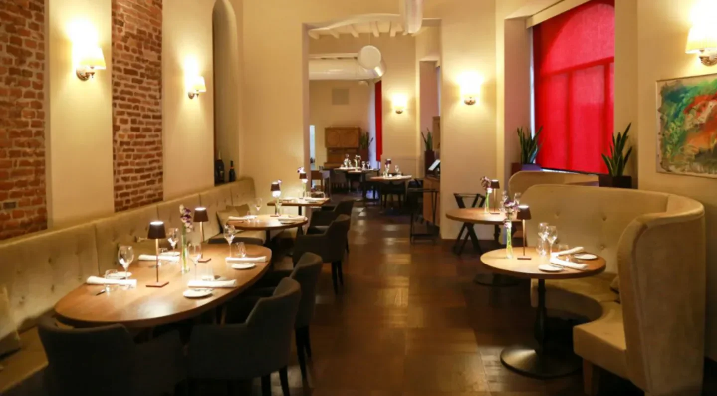 Elegant interior of L’Alchimia restaurant in Milan, with stylish tables and lighting.