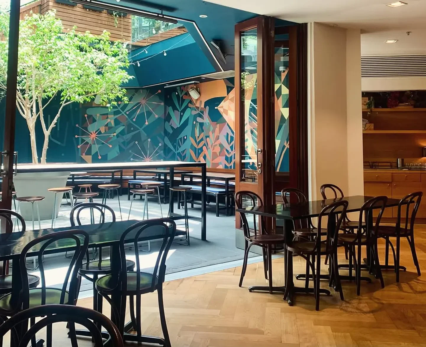 Stylish dining area at Lalla Rookh restaurant in Perth with outdoor patio and mural.