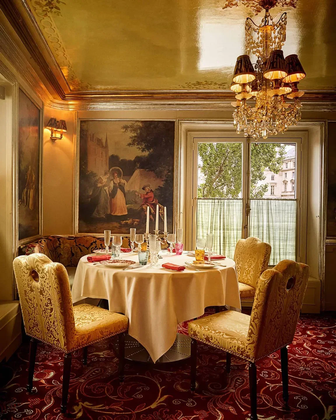 Elegant dining room at Lapérouse restaurant in Paris, featuring a chandelier and historical artwork.