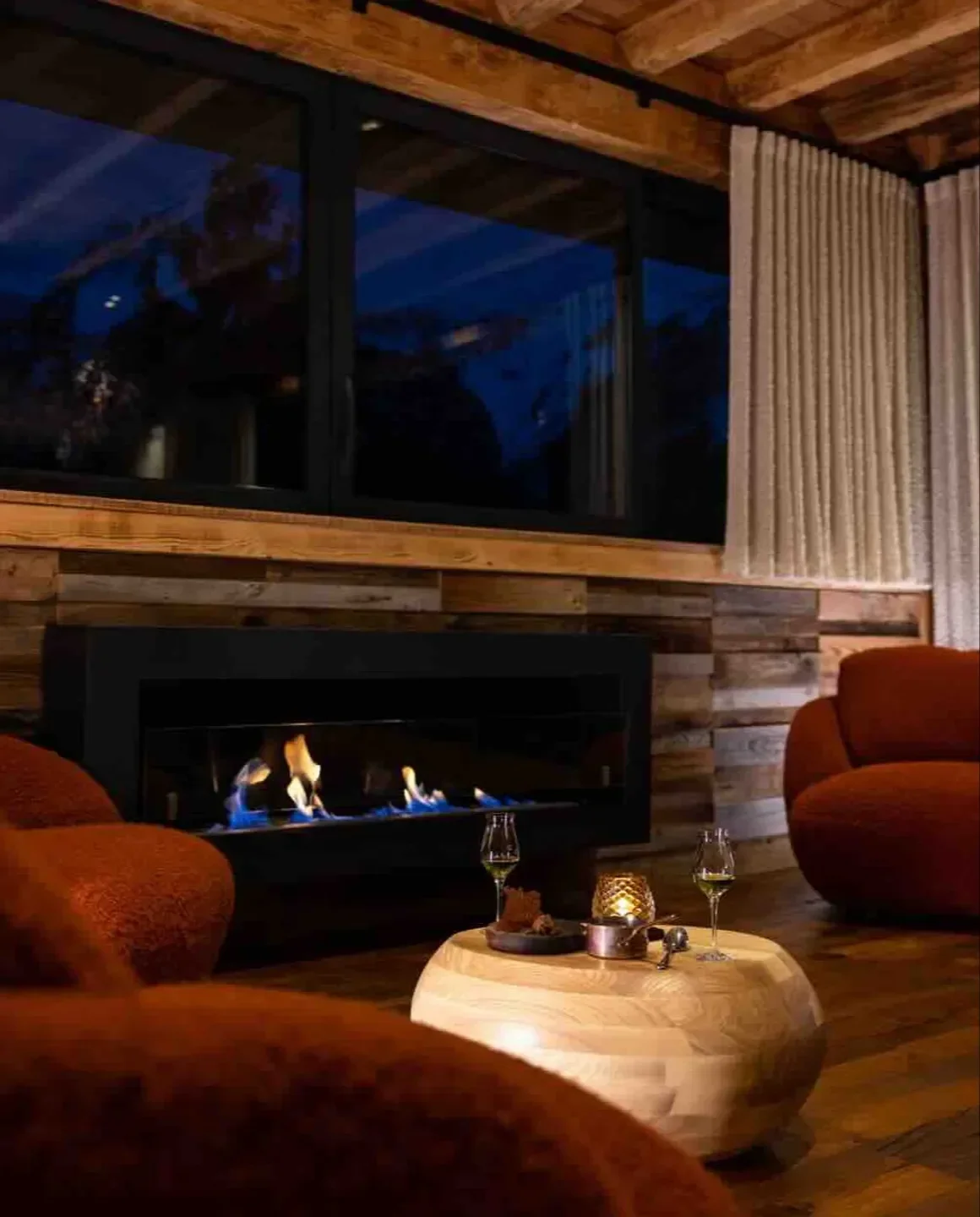 Cozy fireplace at L'Auberge de Montmin restaurant in Annecy with soft seating and drinks.