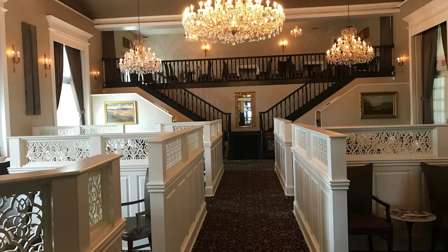 Elegant dining area at Laury’s Restaurant, Charleston, with chandeliers and staircase