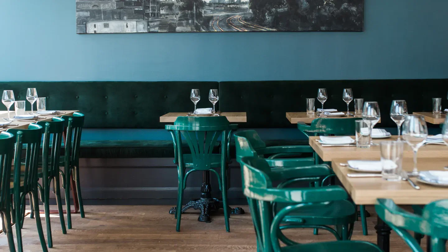 Interior of Lawrence restaurant in Montreal, featuring green chairs and elegant table settings