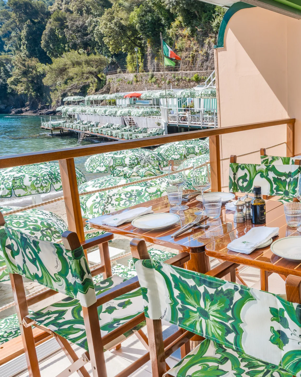Le Carillon Portofino beach club dining area with patterned chairs and umbrellas overlooking the Italian Riviera sea.