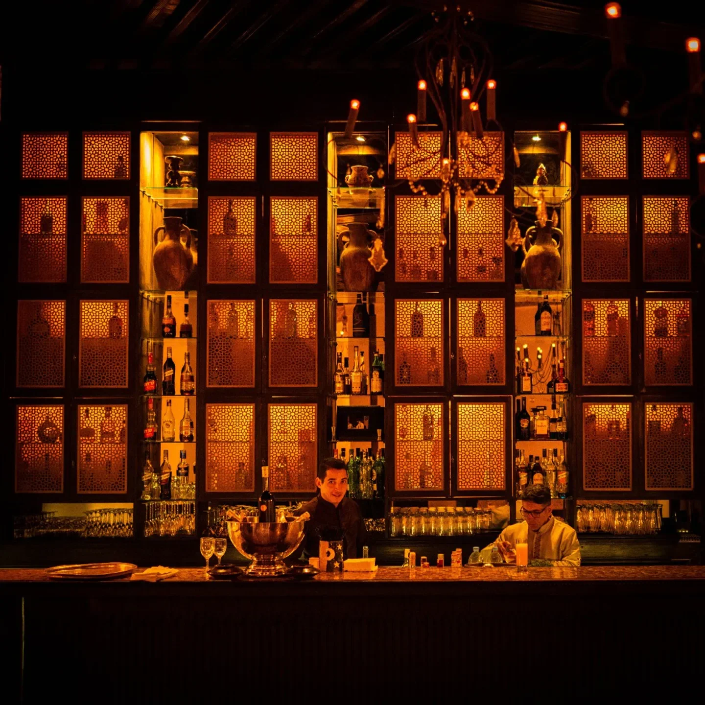 Interior of Le Foundouk restaurant in Marrakech with bartenders and ornate shelving.